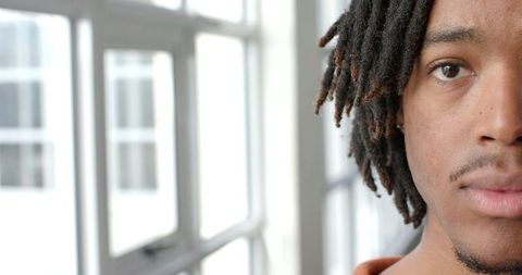 Contemplative african american man gazing through multi-pane window with soft daylight