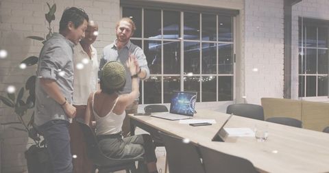 Startup team celebrating late-night win in modern conference room with laptop display