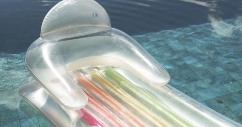 Transparent inflatable lounger floating on mosaic tiled pool with multicolor air chambers