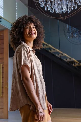 Smiling african american woman looking up in modern lobby with crystal chandelier