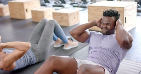 Fit Couple Performing Sit-Ups in Gym Setting