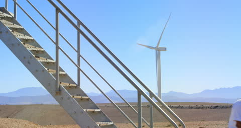 Engineer Descending Wind Turbine Stairs with Turbine Background