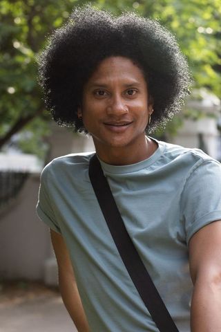 Sunlit african american man with afro wearing mint tee and crossbody strap urban casual portrait