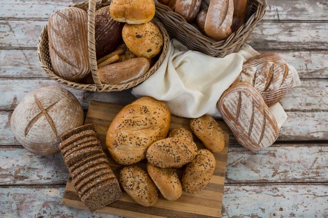 Various types of bread in wicker basket on wooden surface