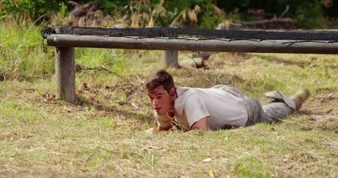 Military Training Recruits Crawling Under Hurdles in Obstacle Course Challenge