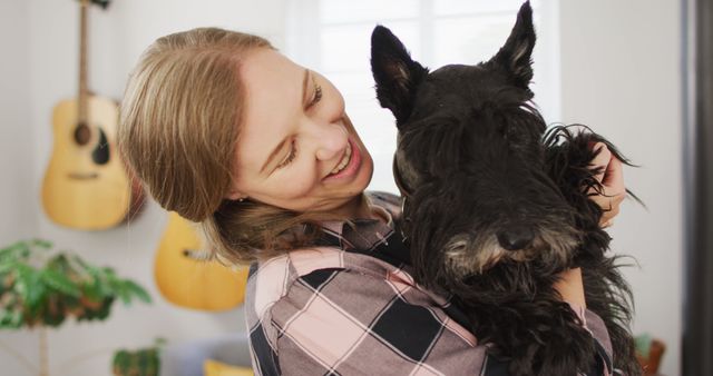 Portrait of caucasian woman holding her dog and smiling at home - Download Free Stock Photos Pikwizard.com