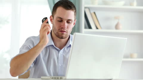Focused Man Working at Home Using Laptop and Smartphone