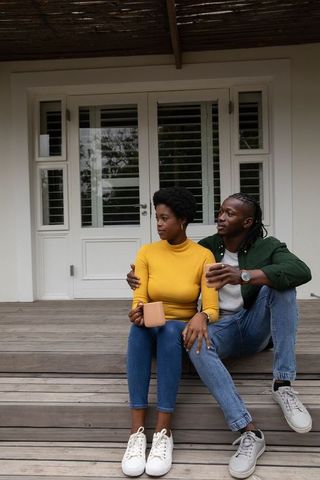 Couple relaxing on porch with warm drinks under pergola