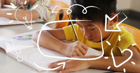 Focused schoolboy writing in workbook wearing yellow shirt with playful white doodle overlays