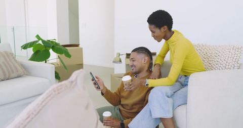 Couple Relaxing on New Beige Couch Among Moving Boxes