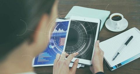 Businesswoman holding tablet with hud overlay and financial charts, coffee notepad on desk