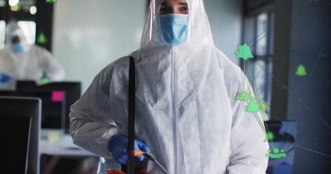Disinfection Specialist Wearing Full PPE Spraying Office Workstations with Fogger for Sanitation