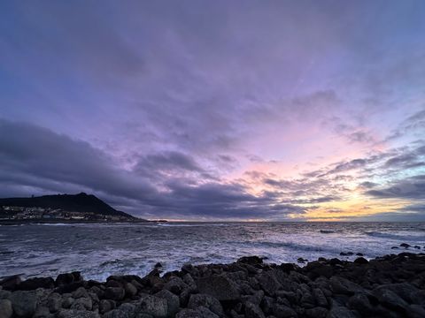 Colorful sunset over rocky beach shore with dark clouds