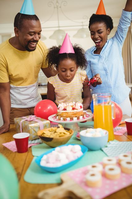 Family celebrating a child's birthday at home with cake, balloons, and gifts. Perfect for use in advertisements, family-oriented content, and articles about family celebrations, birthdays, and home gatherings.