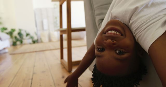 Portrait of happy african american boy upside down in living room at home. Domestic life, childhood and lifestyle, unaltered.