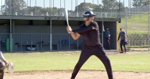 Batter Preparing to Swing at Local Baseball Field with Teammates Watching from Dugout