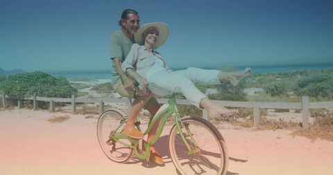Joyful Senior Couple Tandem Biking at Beachfront