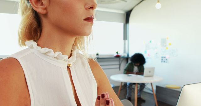 Woman Meditating in Bright Office With Colleague Working in Background - Download Free Stock Images Pikwizard.com