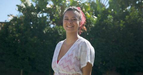 Smiling woman in crochet cover-up and swimsuit in sunny garden