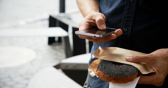 Man Holding Smartphone and Pastry with Poppy Seeds Outdoor - Download Free Stock Images Pikwizard.com