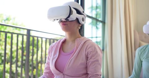 Young Woman Practicing Virtual Reality Meditation on Balcony Wearing White VR Headset