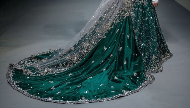 Emerald satin gown with embellished silver train gliding on runway with sheer beaded overlay