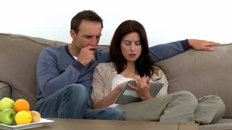 Couple Relaxing on Sofa Using a Tablet Device