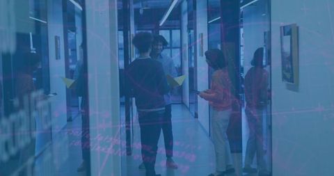 Coworkers collaborating in glass corridor holding yellow folder and phone, orange jacket