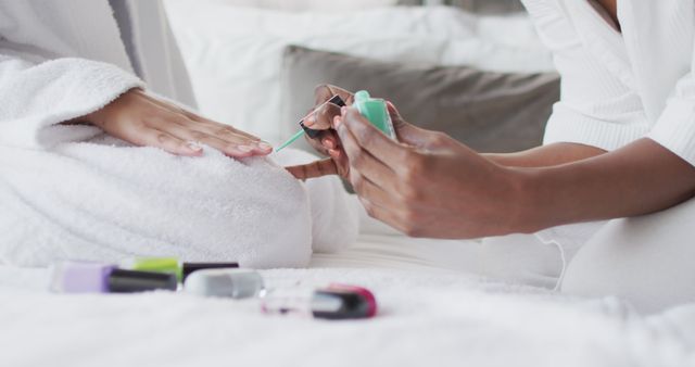Close-up focusing on nail painting activity during a relaxing spa day at home. Ideal for use in self-care, beauty, and wellness content. Suitable for promoting spa services, at-home manicure kits, and personal care brands.