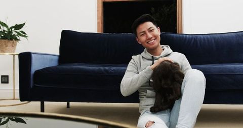 Young man enjoying relaxed moment with puppy in modern living room