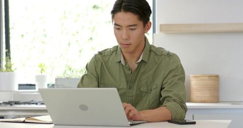 Focused Young Man Working on Laptop in Bright Kitchen