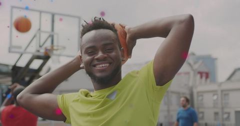 Smiling athlete holding basketball behind head on urban outdoor court preparing confident game shot