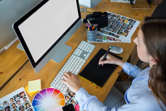 Female graphic designer using graphics tablet at desk in office