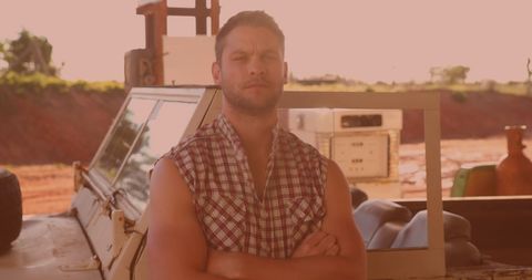 Confident Man in Sleeveless Shirt Standing by Car on Sunny Day