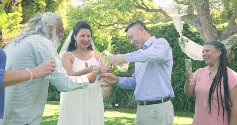 Senior Couple and Friends Toasting with Champagne in Garden