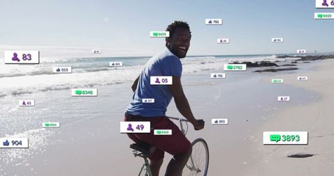 Smiling cyclist riding along beach with social media interaction overlays