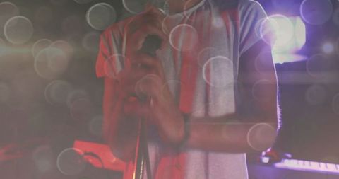 Male singer gripping mic stand on stage with sunshine flare effects