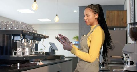 African american barista using tablet behind modern cafe espresso machine and grinder