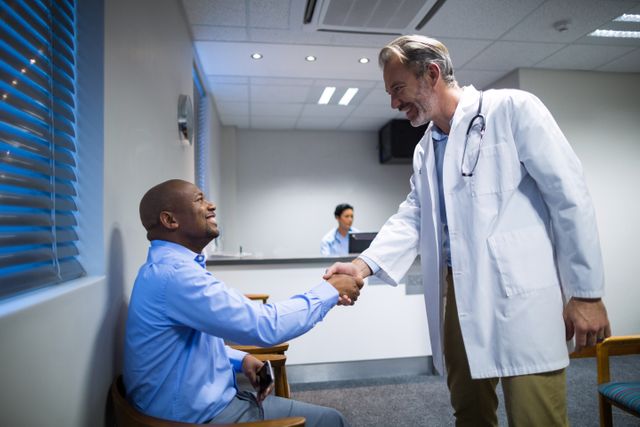 Male doctor shaking hands with patient in hospital