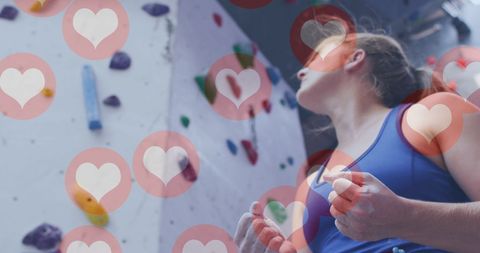 Caucasian Woman Preparing to Climb Gym Wall with Hearts Overlay