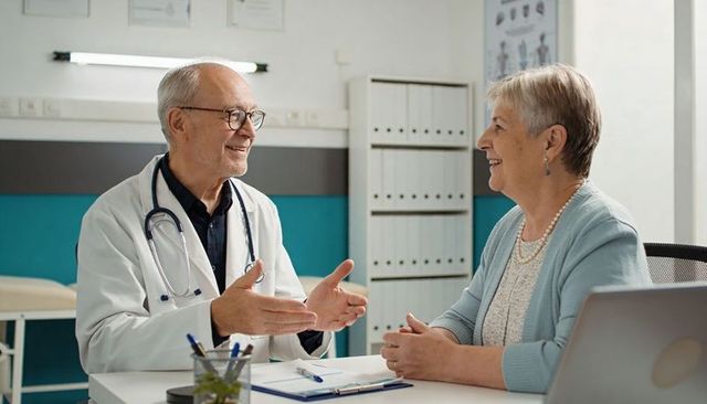 Senior doctor consulting smiling senior patient during medical consultation in clinic