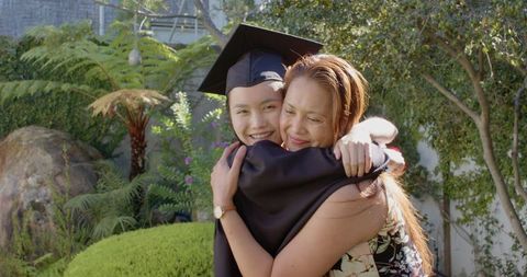 Asian Graduate Daughter Embracing Mother in Garden Celebration