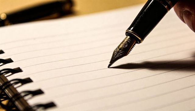 Fountain Pen Nib Hovering Above Lined Spiral Notebook with Dramatic Shadow