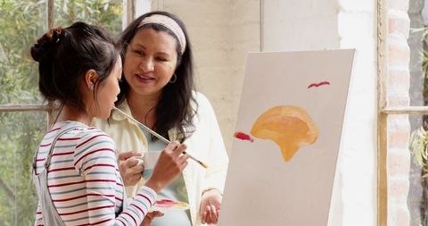 Diverse female artists painting on canvas in art studio