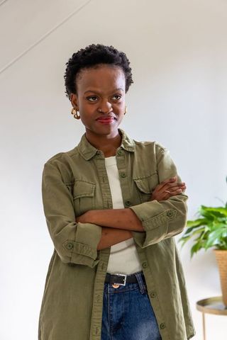 Confident african american woman standing arms crossed wearing olive overshirt and jeans