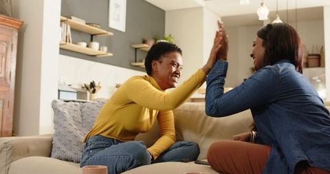 Diverse Female Friends Enjoying a High-Five in Cozy Living Room
