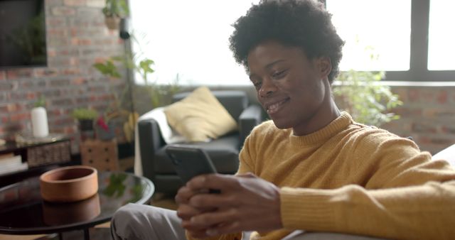 Relaxed Young Man Smiling and Texting on Smartphone in Cozy Living Room - Download Free Stock Images Pikwizard.com