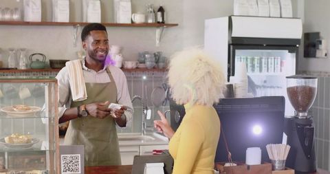 Barista Processing Payment from Smiling Customer in Modern Cafe