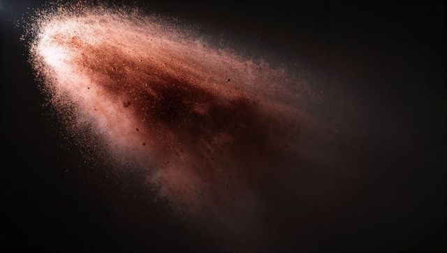 Erupting reddish-brown powder plume in dark studio