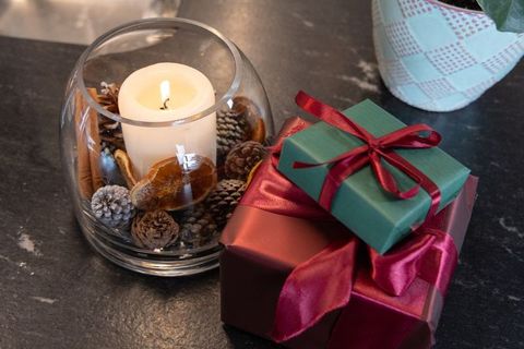 Glowing pillar candle centerpiece with potpourri and wrapped burgundy and green gifts